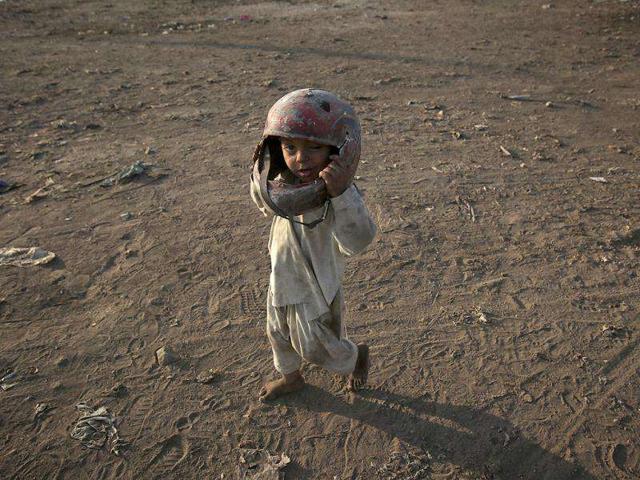 Three-year-old Sabir wears an old helmet on his head, which he found in a dumping ground, while playing in a Karachi slum. (Reuters)