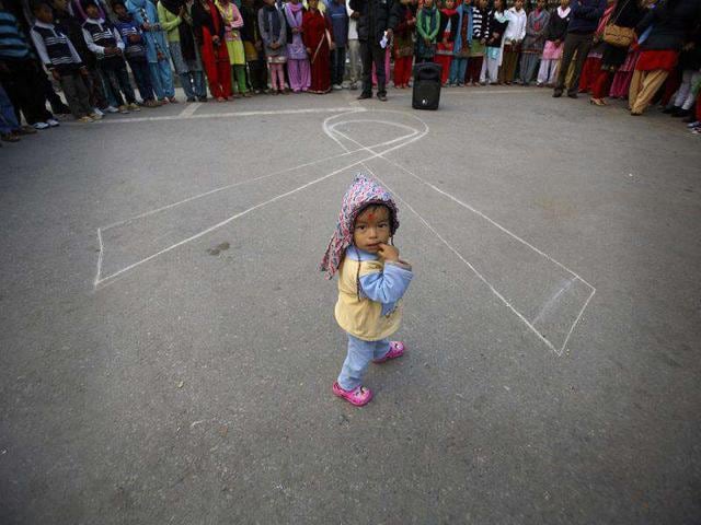 A child looks up while walking past the symbol of a ribbon to mark the upcoming World Aids Day in Kathmandu.