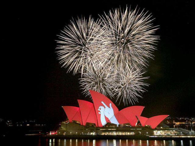 Fireworks burst behind the Sydney Opera House that is bathed in red light with a figure of two hands in Australia as part of a global campaign to create an AIDS-free generation by 2015. Over 50 landmarks and iconic monuments around the world will turn red on Dec 1, in support of the campaign.