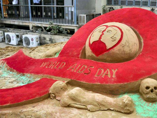 Sand artist Subal Moharana makes AIDS insignia in Bhubaneswar.