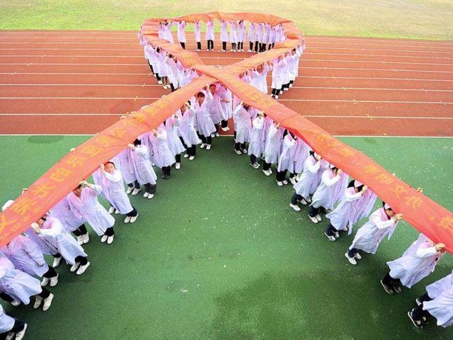 Nurses stand to form a Red Ribbon while holding a banner to mark World AIDS Day at a medical school in Yangzhou, Jiangsu province.