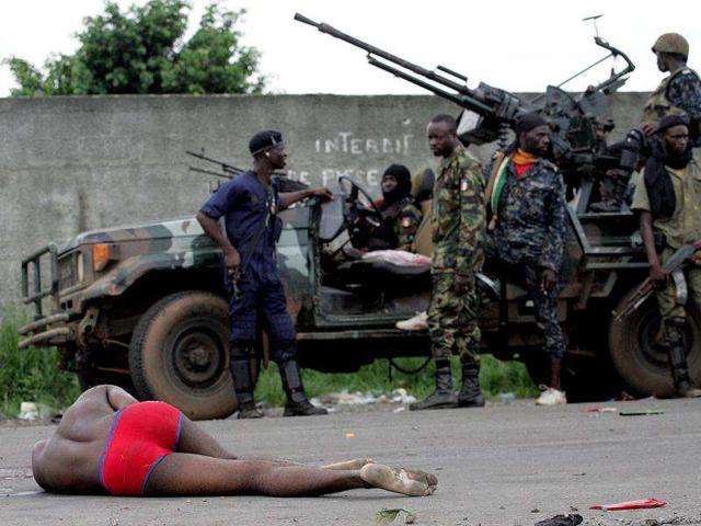 Forces loyal to Ivorian presidential claimant Alassane Ouattara wait behind an injured man in the capital Abidjan in this file photo. The International Criminal Court confirmed former Ivory Coast President Laurent Gbagbo had been detained in The Hague on November 30, 2011, following his arrest on charges of crimes against humanity and transfer from Ivory Coast overnight. (Reuters)