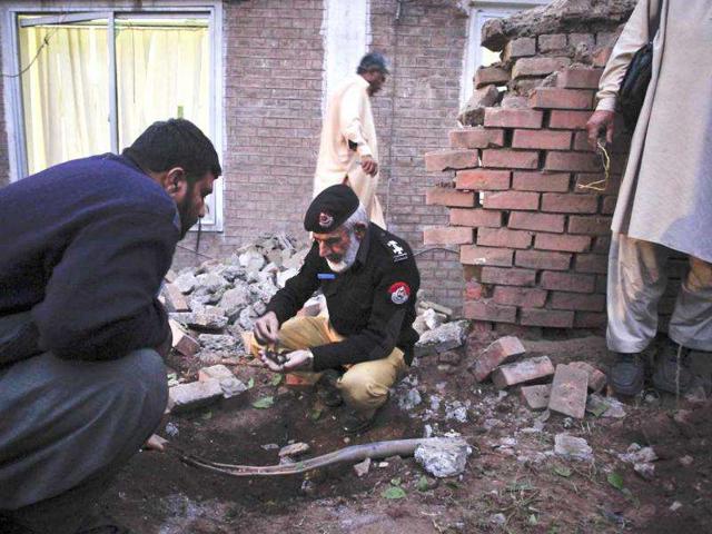 Policemen-collect-shrapnel-from-the-site-of-a-bomb-explosion-which-struck-the-district-coordination-officer-building-in-Peshawar