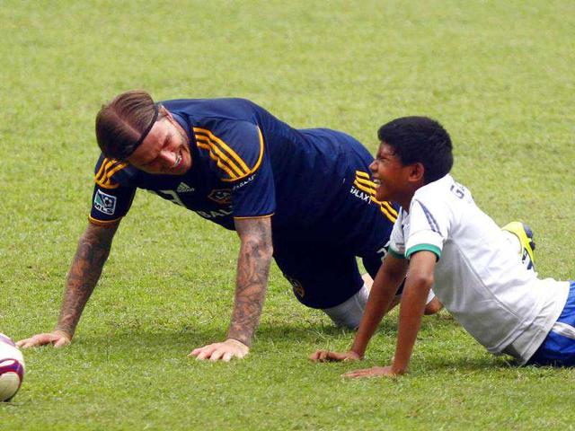 Los-Angeles-Galaxy-s-midfielder-David-Beckham-smiles-as-he-does-push-ups-with-an-Indonesian-youth-during-a-soccer-coaching-clinic-at-Gelora-Bung-Karno-stadium-in-Jakarta-Indonesia
