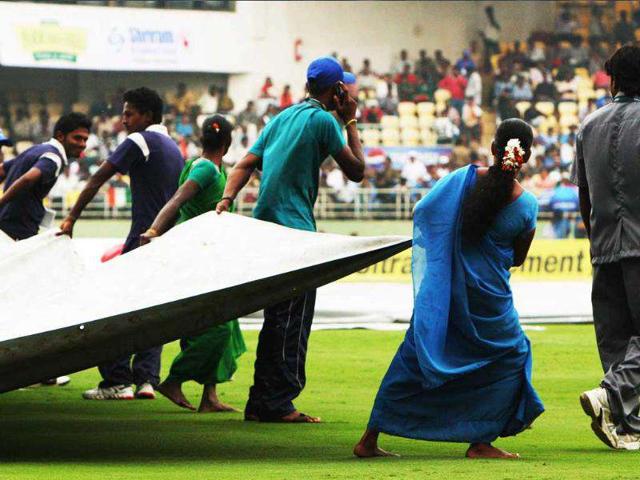 Groundsmen pull covers as it rained before the 2nd ODI between India and West Indies, at Dr YS Rajasekhara Reddy Cricket Stadium.