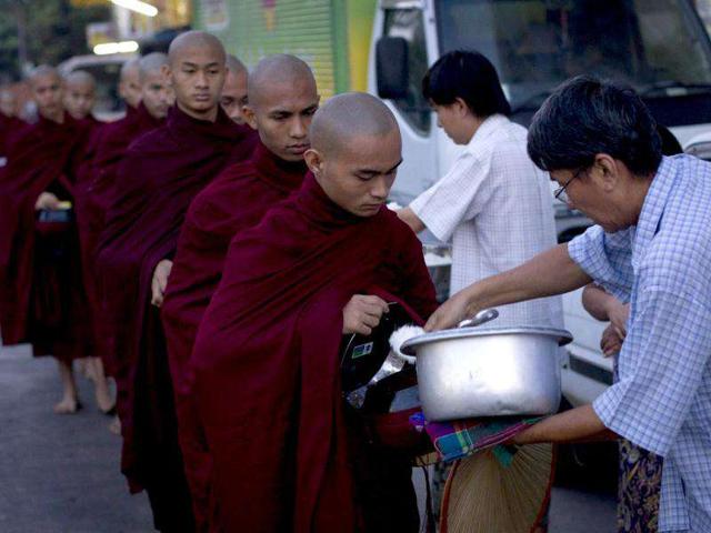 Buddhist monks walk along a road as they collect alms from devotees in Yangon, Myanmar. AP Photo/Vincent Thian