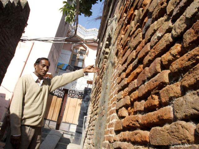 Tirth Ram, a resident of Gharota village in Punjab's district of Pathankot, showing the remaining walls of Dev Anand's native house. (Munish Byala/HT)