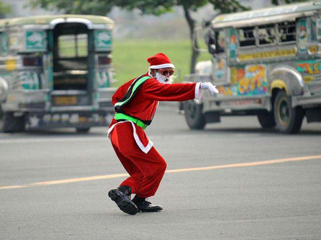 Philippine traffic enforcer Ramiro Hinojas, dressed as Santa Claus costume, directs traffic along a major road in Manila.