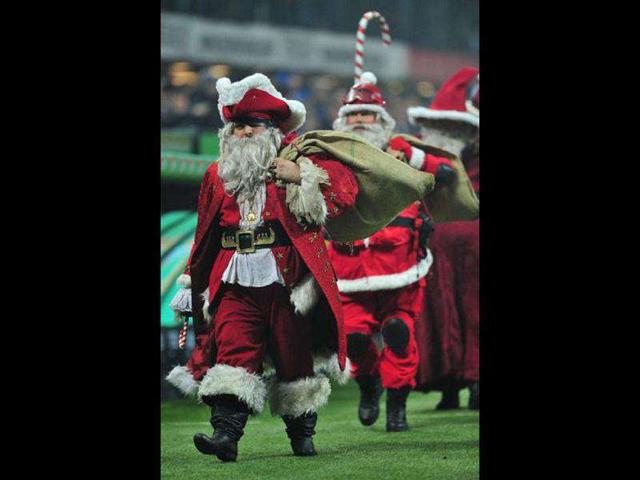 People dressed as Santa Claus walk on the pitch prior the Italian Serie A football match between AC Milan and Chievo at San Siro Stadium in Milan.