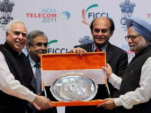 Prime Minister Manmohan Singh being presented a memento with Green Certificate by FICCI President, Harsh Mariwala (2nd R) and Union Minister for Communications and IT, Kapil Sibal during the inaugural ceremony of India Telecom 2011 'm-Powering India' at DRDO bhawan.