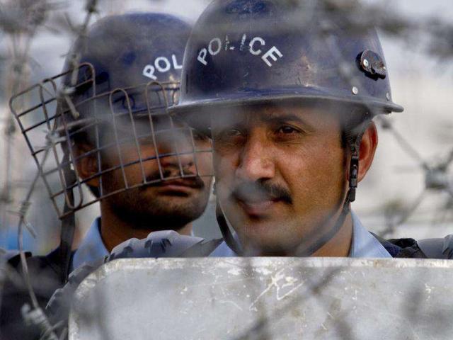 Pakistani police officers stand guard behind a barbed wire as they look towards protestors during an anti Nato rally in Islamabad, Pakistan. AP Photo/Anjum Naveed