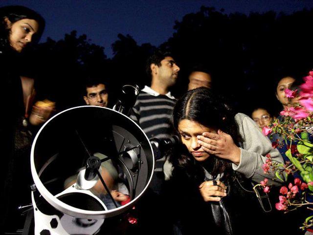 People watch the lunar eclipse from Nehru Planetarium in New Delhi on Saturday. (HT Photo/Arijit Sen)