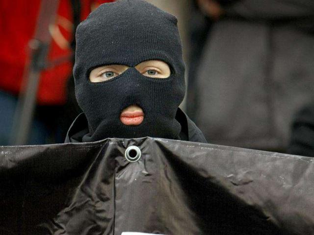 A young masked Russian nationalist holds a banner during their rally at Bolotnaya Square, on an island in the Moscow River adjacent to the Kremlin in Moscow. Russian nationalists are rallying in downtown Moscow, demanding a bigger say for ethnic Russians in the country's politics and marking the first anniversary of a violent nationalist riot just outside the Kremlin.