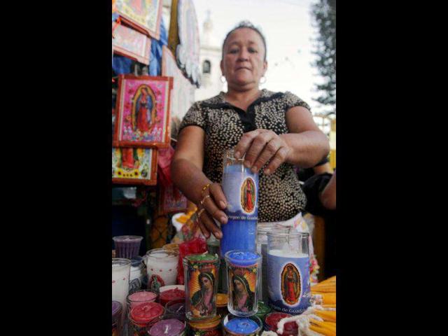 A woman sells candles with images of the Virgin of Guadalupe in San Salvador. Reuters/Luis Galdamez