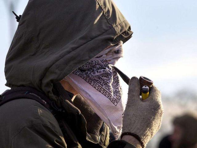 A protester smokes his pipe through a handkerchief covering his face while blocking the entrance to Port Authority in Vancouver, British Columbia. Reuters Photo