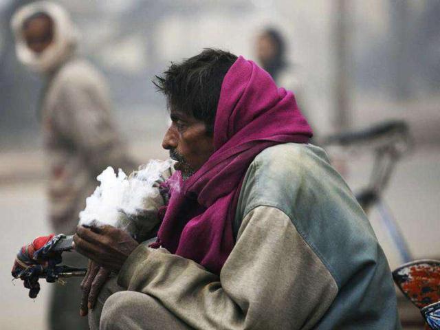 A rickshaw puller smokes tobacco as he waits for passengers early morning in Allahabad. AP Photo