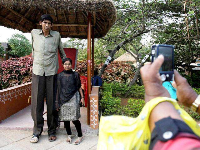 A visitor poses with Polipaka Gattaiah, who stands at seven-and-a-half feet and claims to be the tallest man in India, at the arts and crafts centre in Hyderabad. Reuters Photo