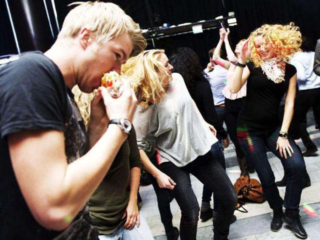 A man eats a sandwich while dancing with his friends during one of the Lunch Beat sessions held at the Culture House in central Stockholm. The Lunch Beat is a growing movement in Sweden, mixing a work break with a bit of disco fever. AFP Photo