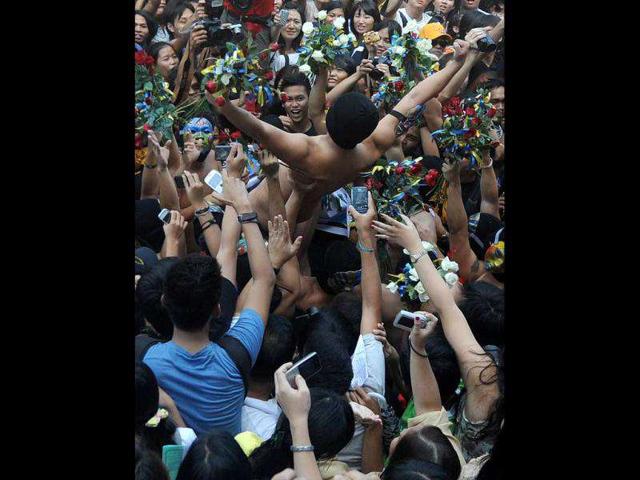 A nude member of a university fraternity (C) is carried through a crowd of fellow students during the traditional 'Oblation Run' at the University of the Philipppines campus in suburban Manila. The nude run is used each year to draw attention to the major issues of the day in the Philippines. (AFP/Noel Celis)