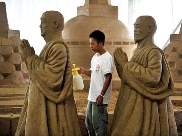 A worker sprays water on sand sculptures featuring world famous landmarks during the 1st Sand Sculptures Festival at cultural park in Sentul outside of Jakarta, Indonesia. International artists from 11 countries created 40 large sand sculpture pieces of figures and land marks for the first Sand Sculptures Festival. (AFP/Bay Ismoyo)