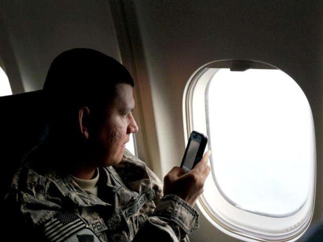 US Army Sergeant Carmelo Pena from LA California of the 2-82 Field Artillery, 3rd Brigade, 1st Cavalry Division, takes a photograph as the plane decends for it landing at their home base of Fort Hood, Texas after being part of one of the last American combat units to exit from Iraq.