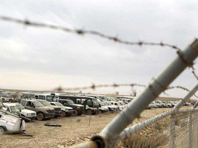 Abandoned vehicles stand in a lot behind a barbed wire fence inside Camp Adder, the last United States base in Iraq, near Nasiriyah.