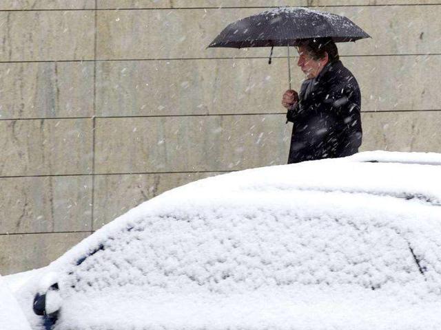 A man walks through the snow protected by his umbrella, in Geneva, Switzerland. AP Photo