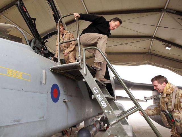 British Prime Minister David Cameron (C) descends a ladder after being shown the cockpit of a Tornado fighter jet by members of the Royal Air Force 12 (B) squadron during a pre-Christmas visit to greet British troops at Kandahar airfield in Kandahar. AFP/Pool/Jeff J Mitchell