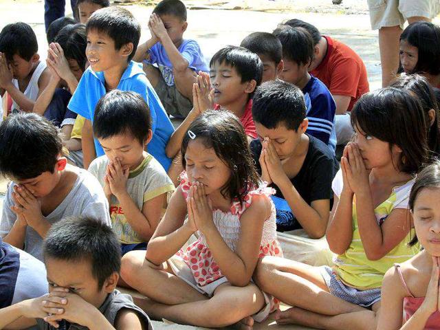 Typhoon Washi survivors pray before the start of a trauma counselling session by volunteers from humanitarian agency World Vision, outside an evacuation center in the southern Philippines city of Cagayan de Oro. Reuters/Erik De Castro