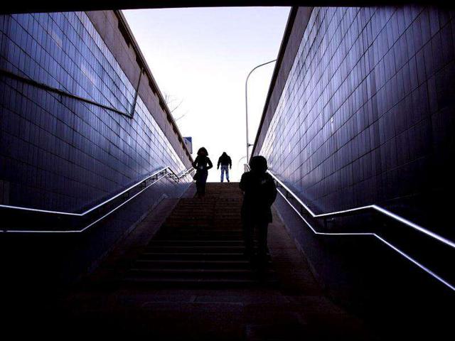 Pedestrians react as a strong wind blows while they walk up and down a stairway leading to a tunnel, on a cold winter's day in Beijing.