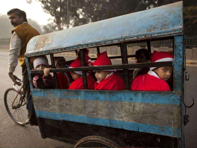 Children wearing festive clothing ride in the back of a bicycle rickshaw on their way to a Christmas party at a kindergarten on the last day before school holidays in New Delhi. AP Photo/Kevin Frayer