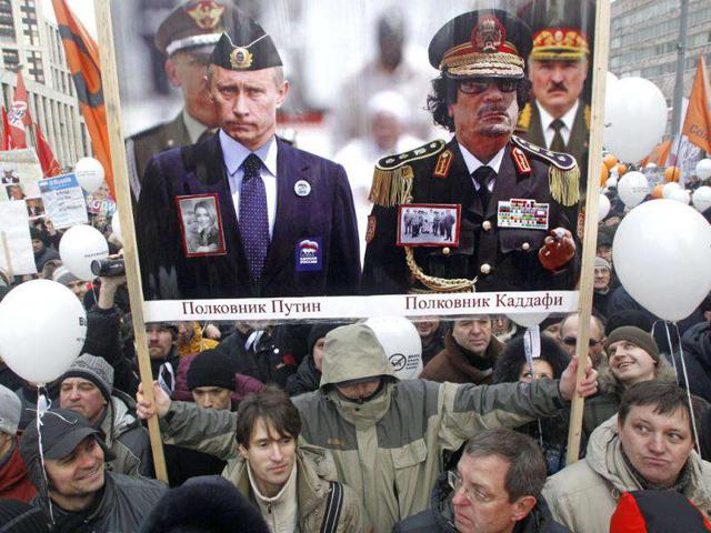 Protesters hold a poster depicting Russian Prime Minister Vladimir Putin (L), former Libyan leader Moammar Gadhafi (second from right) and Belarus President Alexander Lukashenko (R) as they gather to protest against alleged vote rigging in Russia's parliamentary elections on Sakharov avenue in Moscow. AP Photo/Mikhail Metzel