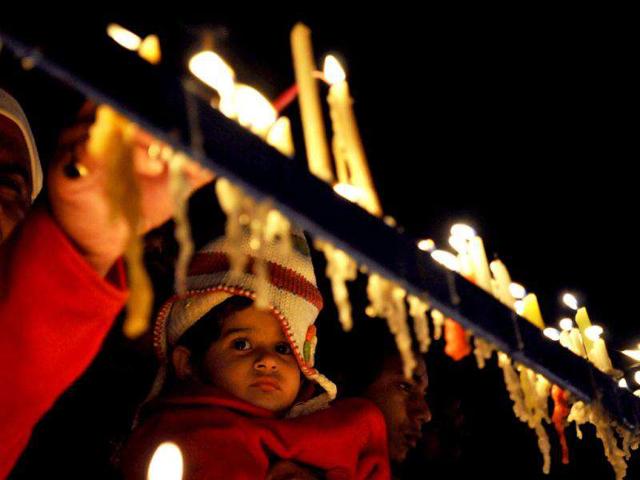A child looks at candles lit by people offering prayers at the Sacred Heart Cathedral on Christmas in New Delhi.