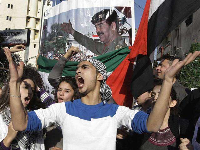 Members and supporters of the Socialist Arab Lebanon Vanguard Party carry a poster of former Iraqi President Saddam Hussein and Iraqi flags as they shout slogans against the US during a march in front of the US embassy in Aukar, east of Beirut, Lebanon, to celebrate the withdrawal of American troops from Iraq. AP Photo/Bilal Hussein