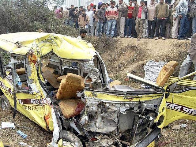 People look at the ill-fated school bus which collided with a truck in Ambala claiming 12 lives. PTI Photo