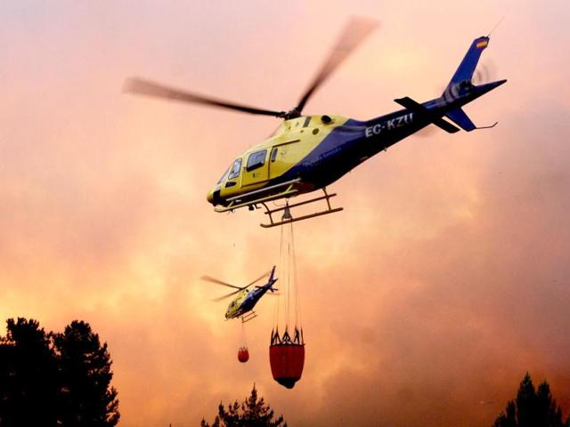 Helicopters fight a massive forest fire affecting the commune of Quillon, in southern Chile's Bio Bio region, some 500 Km south of Santiago