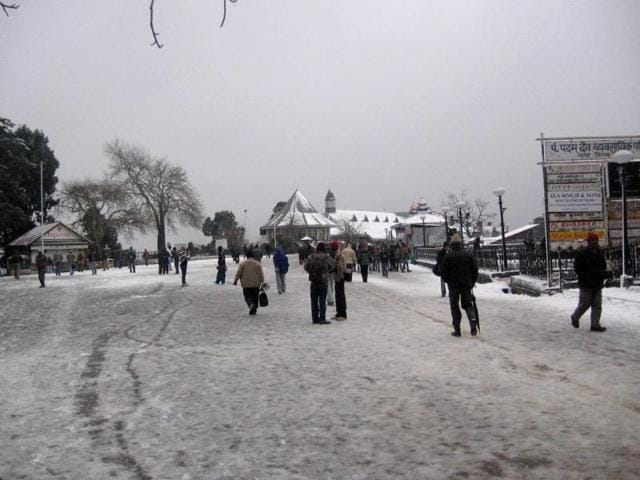 Tourists and local people throng a street to enjoy fresh snowfall in Shimla.