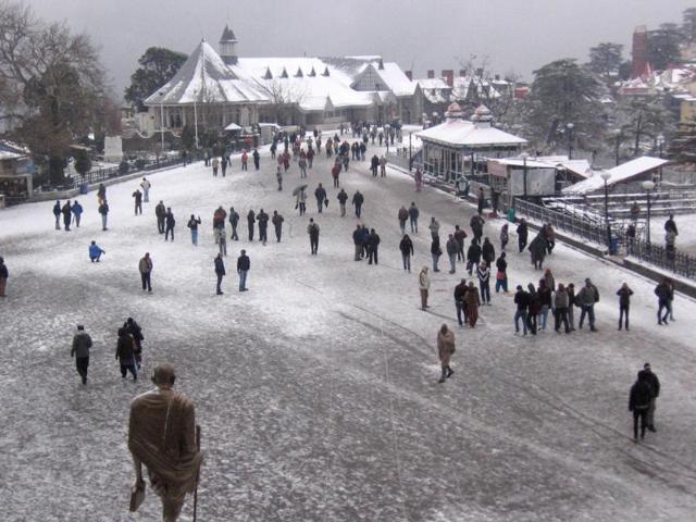 Tourists and local people throng a street to enjoy fresh snowfall in Shimla.