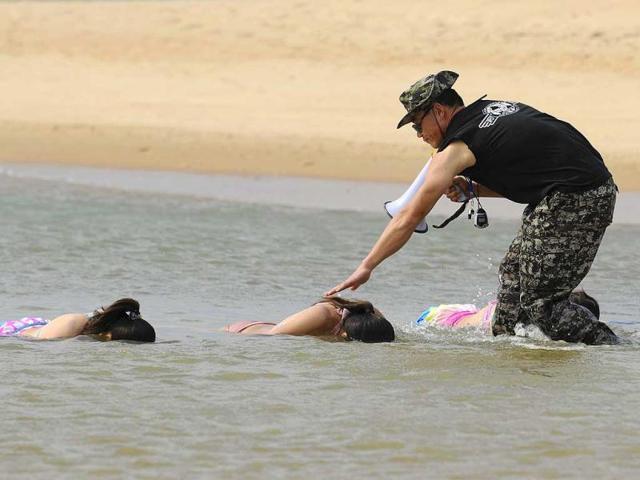 Trainees dressed in swimming suits sink their heads into the sea under the instructions of a trainer from Tianjiao Special Guard/Security Consultant Ltd. Co. during a training session in Sanya, China. All trainees will have to undergo 8-10 months of training to develop sufficient skills to serve their clients.(Reuters)
