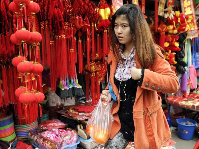 A woman passes Chinese New Year decorations for sale on a street in Shanghai. AFP Photo/Peter Parks.