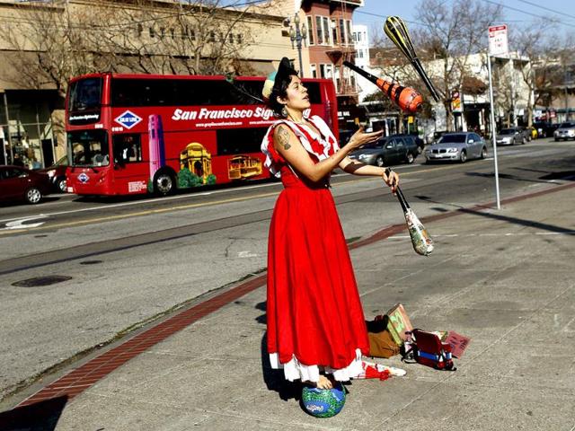 Street performer Carla Milugo juggles on a sidewalk while balancing on a ball in San Francisco, California. Milugo, who performs a variety of tasks, said she is performing for money to purchase a plane ticket to Europe, where she said she will continue her street performances. Reuters Photo/Robert Galbraith