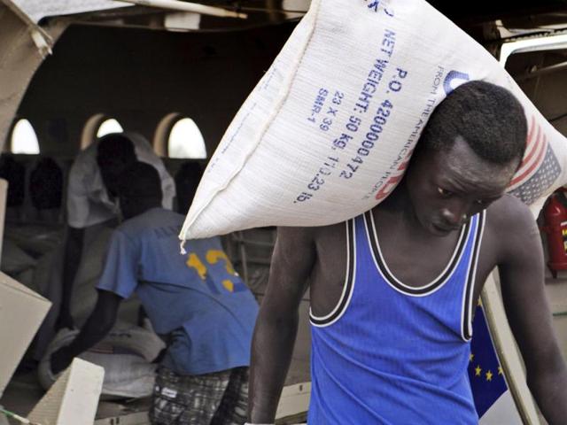 Displaced residents of Pibor County, South Sudan, unload bags of food flown in by the World Food Program ar Pibor airport. (AP Photo)
