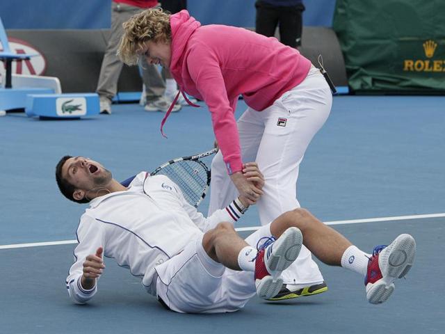 Serbia's Novak Djokovic reacts as his partner Belgium's Kim Clijsters helps him to his feet after he was hit by a ball during an exhibition match before the Australian Open tennis championship in Melbourne. AP photo/Mark Baker