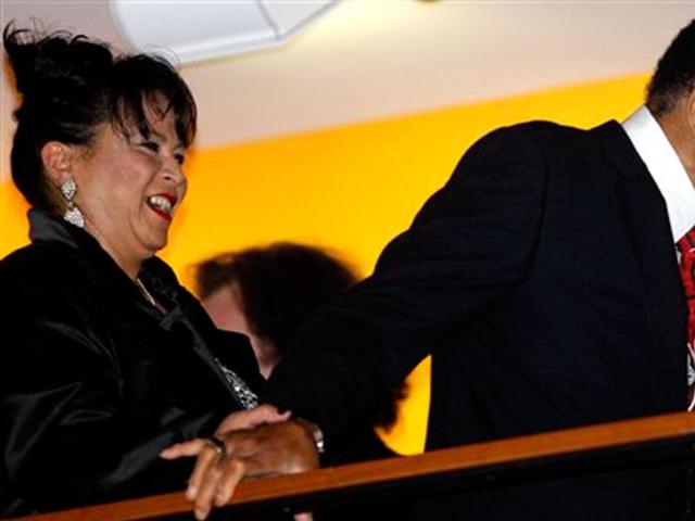 Boxing great Muhammad Ali, with the help of his sister-in-law, Marilyn Williams, left, makes an appearance at a balcony before the celebration for his 70th birthday at the Muhammad Ali Center, in Louisville, Kentucky. Ali turns 70 on Tuesday. (AP Photo/Mark Humphrey)