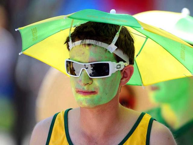 A spectator wears an umbrella hat as he attends the men's singles first round match between Rui Machado of Portugal and David Ferrer of Spain on day two of the 2012 Australian Open tennis tournament in Melbourne. AFP Photo/Nicolas Asfouri