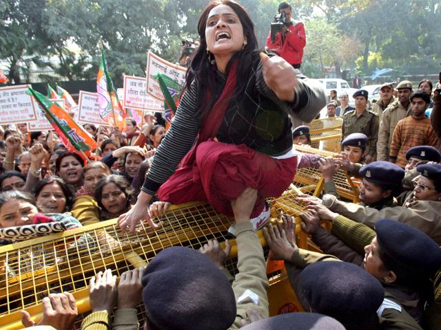 One of the BJP women wing members climbs a police barricade as they protest against Congress general secretary Rahul Gandhi's remarks against party leader Uma Bharti, outside AICC headquarters in New Delhi. PTI Photo