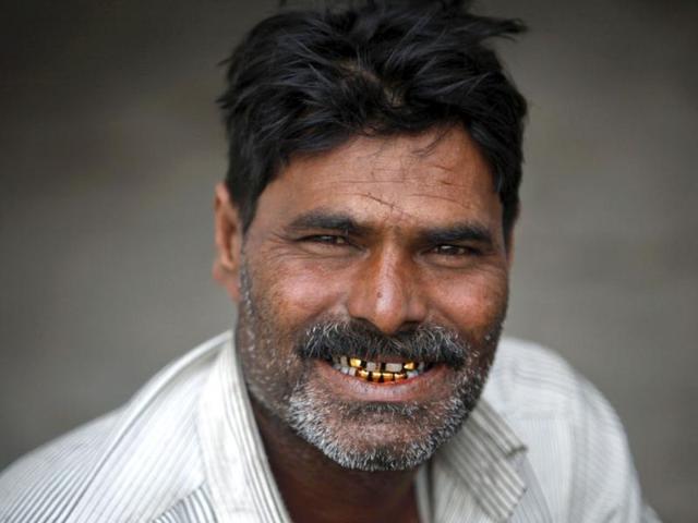 Welljee, 40, a fisherman from India smiles to show his gold ornament-decorated teeth while sitting with others in a police station in Karachi after being detained in Pakistan waters. (Reuters)