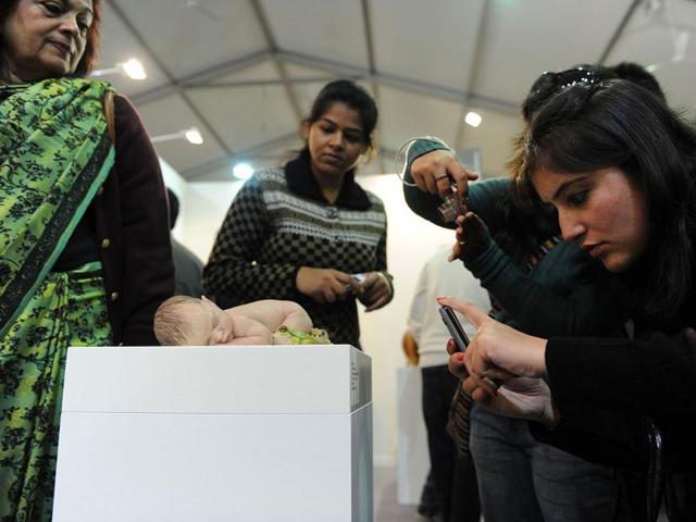 Visitors take pictures of an artwork representing a newborn by Australian artist Sam Jinks at the India Art Fair in New Delhi. AFP Photo/Sajjad Hussain