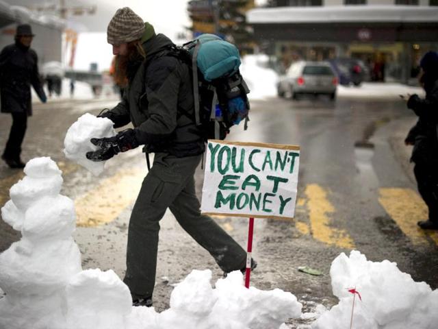 An "Occupy WEF" protester builds a snowman across the street during a protest.(AFP PHOTO / FABRICE COFFRINI)