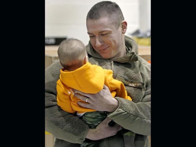 Airman Daniel Fournier, of Mansfield, Conn and the 103rd Security Forces Squadron, admires his three-month-old son Hunter, who was born during deployment, at the Bradley Air National Guard base in East Granby. Twenty-five Connecticut National Guard airmen, who were responsible for security at Bagram Airbase, returned home after July 2011. AP Photo/Charles Krupa